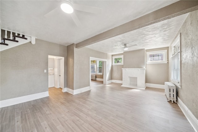 unfurnished living room featuring ceiling fan, radiator heating unit, and light wood-type flooring