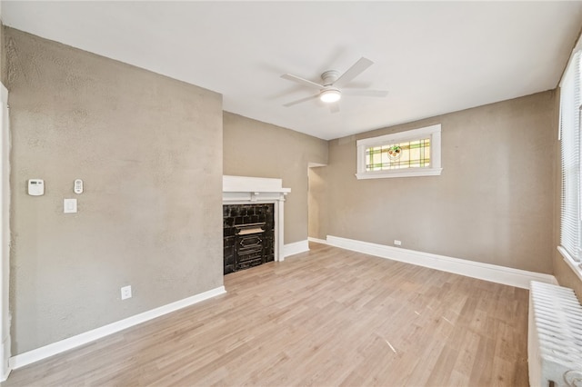 unfurnished living room with radiator, ceiling fan, and light hardwood / wood-style floors