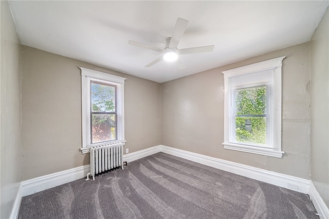 carpeted empty room with ceiling fan, a wealth of natural light, and radiator heating unit