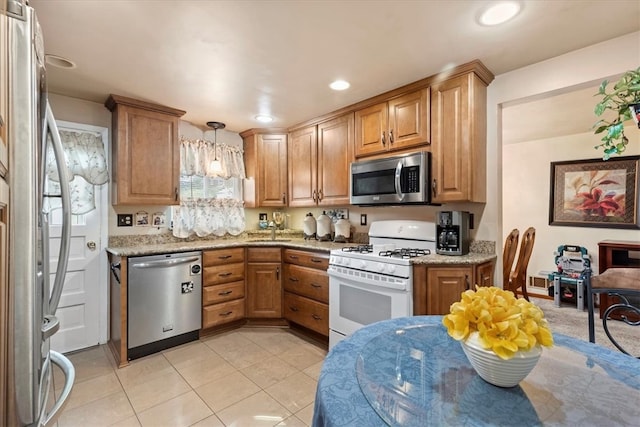 kitchen with pendant lighting, stainless steel appliances, sink, light stone counters, and light tile patterned flooring