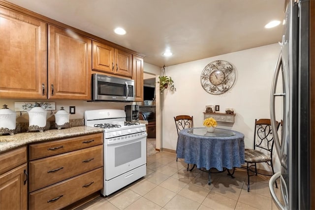 kitchen featuring light stone counters, light tile patterned floors, and appliances with stainless steel finishes