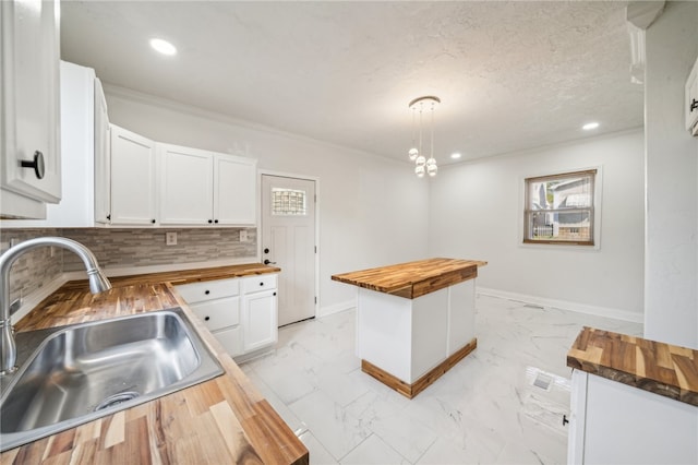 kitchen with white cabinetry, decorative light fixtures, wooden counters, sink, and decorative backsplash