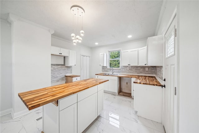 kitchen with decorative light fixtures, white cabinetry, tasteful backsplash, and wooden counters