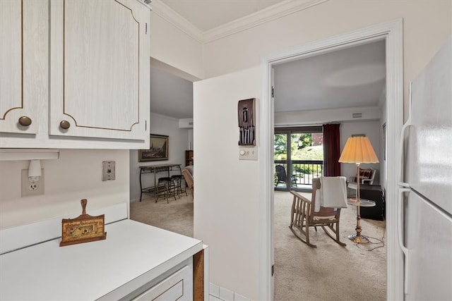 kitchen with ornamental molding, white refrigerator, light brown cabinetry, and light colored carpet