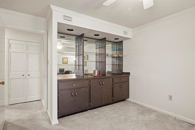 bar featuring ceiling fan, light colored carpet, dark brown cabinets, and crown molding