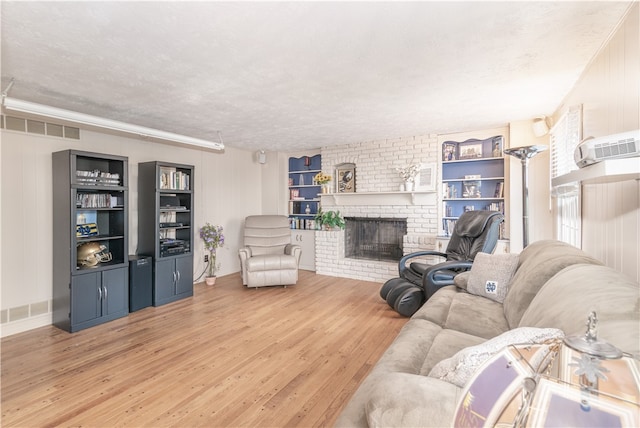 living room with hardwood / wood-style flooring, a fireplace, wooden walls, built in features, and a textured ceiling