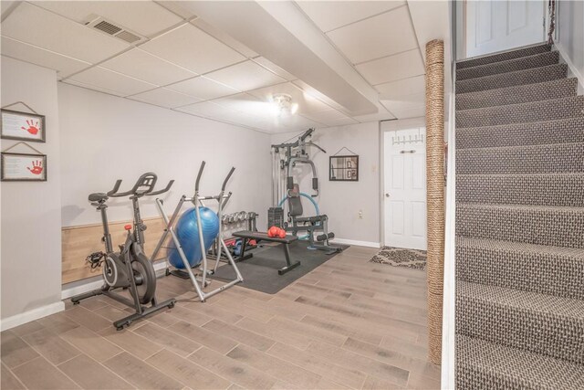 exercise room with hardwood / wood-style floors and a paneled ceiling