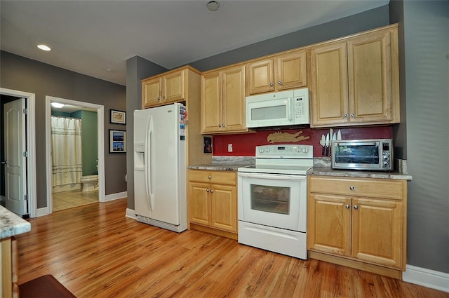 kitchen with white appliances and light hardwood / wood-style floors