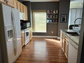 kitchen with light wood-type flooring, light brown cabinets, white appliances, and sink