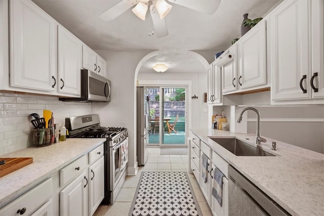 kitchen with light tile patterned floors, stainless steel appliances, sink, ceiling fan, and white cabinets