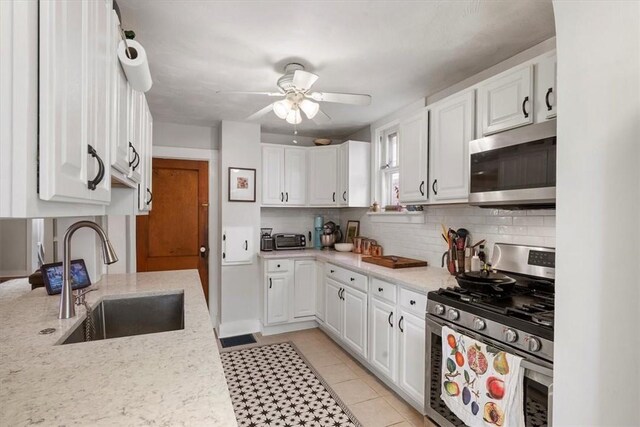 kitchen with white cabinets, light tile patterned floors, appliances with stainless steel finishes, sink, and ceiling fan