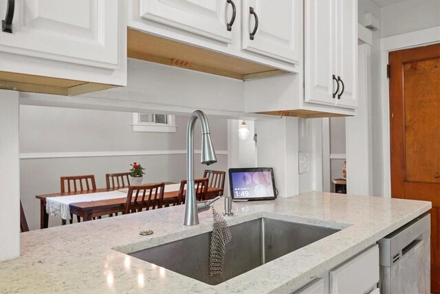 kitchen featuring dishwasher, sink, light stone countertops, and white cabinetry