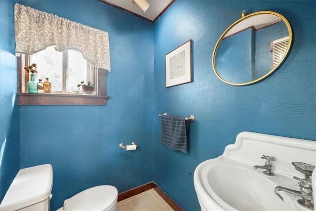 bathroom with toilet, sink, and tile patterned floors