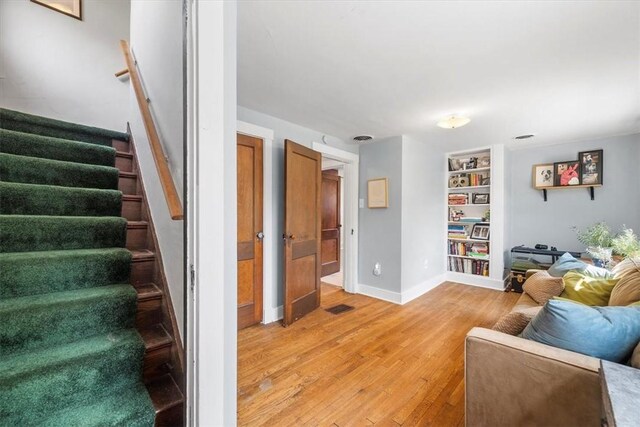 living room featuring built in features and light hardwood / wood-style flooring