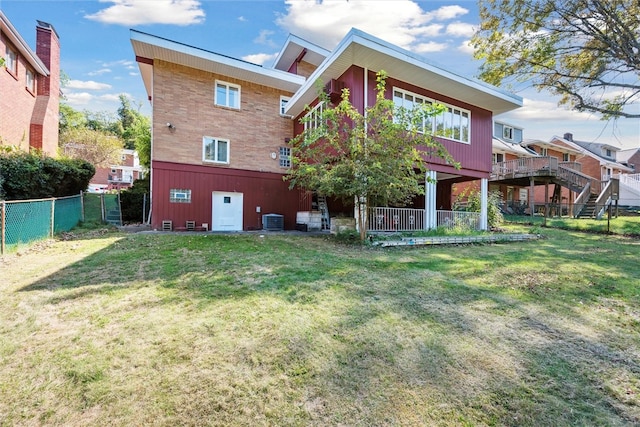 back of property with cooling unit, a yard, and a wooden deck