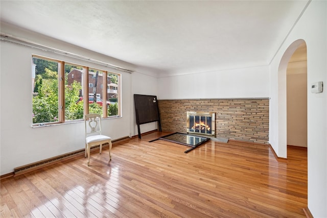 unfurnished room featuring a brick fireplace and hardwood / wood-style flooring