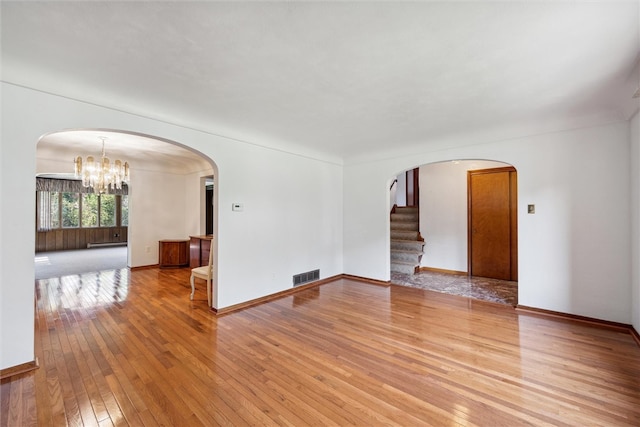 spare room featuring a baseboard radiator, an inviting chandelier, and light hardwood / wood-style flooring