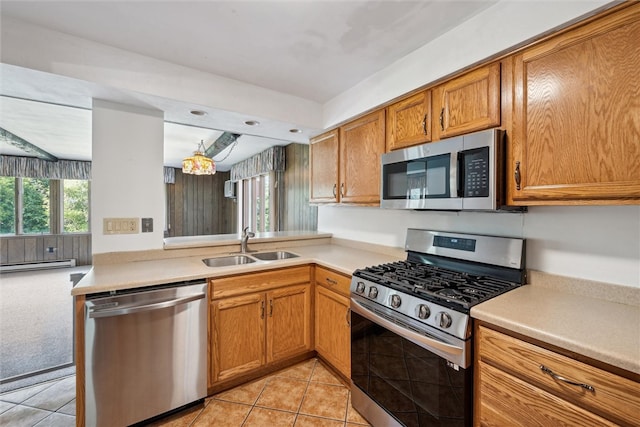 kitchen featuring light tile patterned floors, baseboard heating, stainless steel appliances, sink, and kitchen peninsula