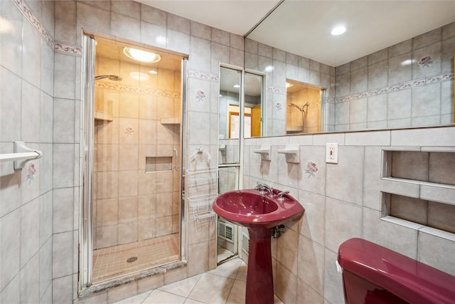 bathroom with tile walls, tile patterned floors, and a shower with door