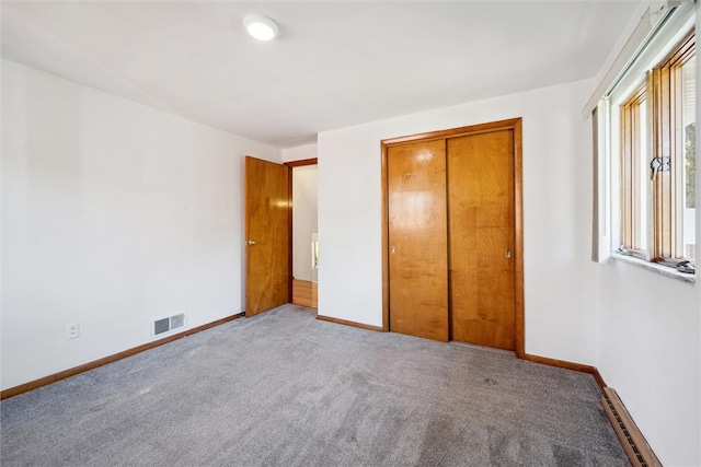 unfurnished bedroom with a closet, a baseboard radiator, and light carpet