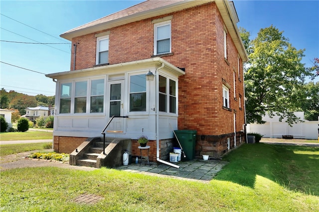 back of house featuring a yard and a sunroom