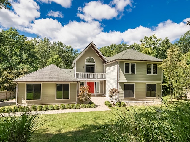 back of property with a balcony and a lawn