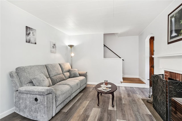 living room with hardwood / wood-style flooring, crown molding, and a brick fireplace