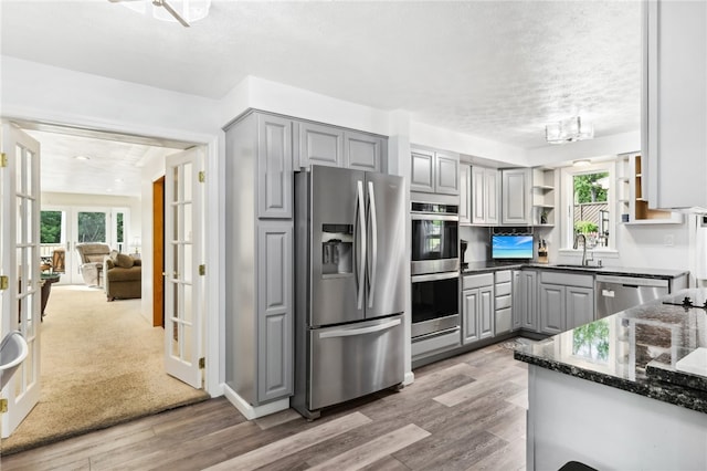 kitchen featuring appliances with stainless steel finishes, gray cabinetry, hardwood / wood-style flooring, and a wealth of natural light