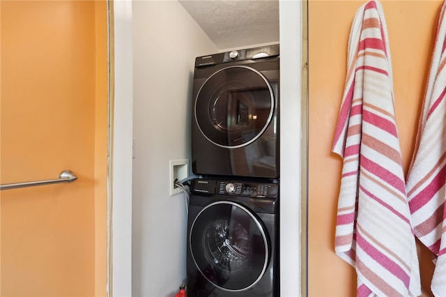 clothes washing area with stacked washing maching and dryer and a textured ceiling