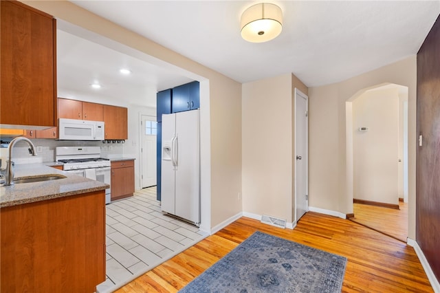 kitchen featuring light hardwood / wood-style flooring, light stone counters, sink, and white appliances