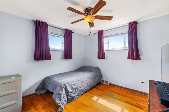 bedroom with multiple windows, hardwood / wood-style floors, and ceiling fan