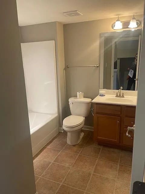 full bathroom featuring tile patterned flooring, washtub / shower combination, vanity, and toilet