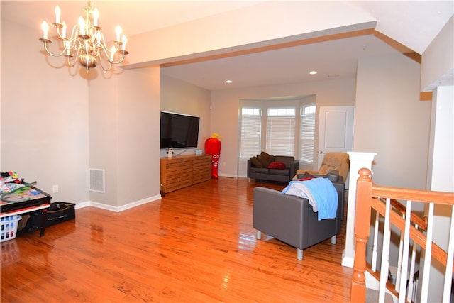 living room featuring lofted ceiling, hardwood / wood-style floors, and a notable chandelier