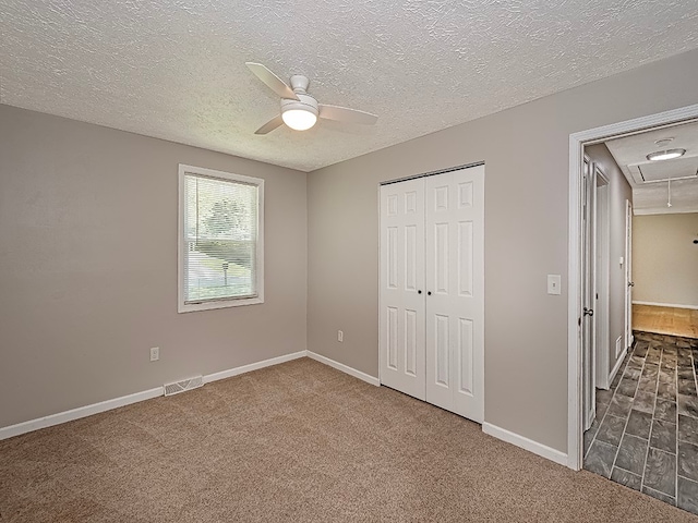 unfurnished bedroom featuring a textured ceiling, dark carpet, ceiling fan, and a closet