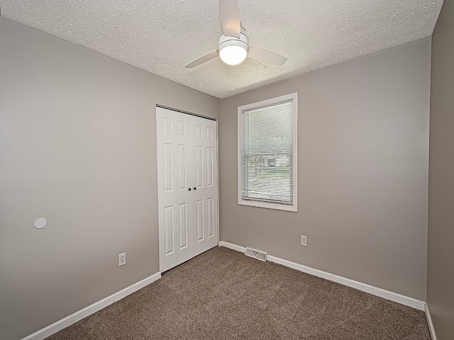 unfurnished bedroom with a textured ceiling, ceiling fan, a closet, and carpet floors