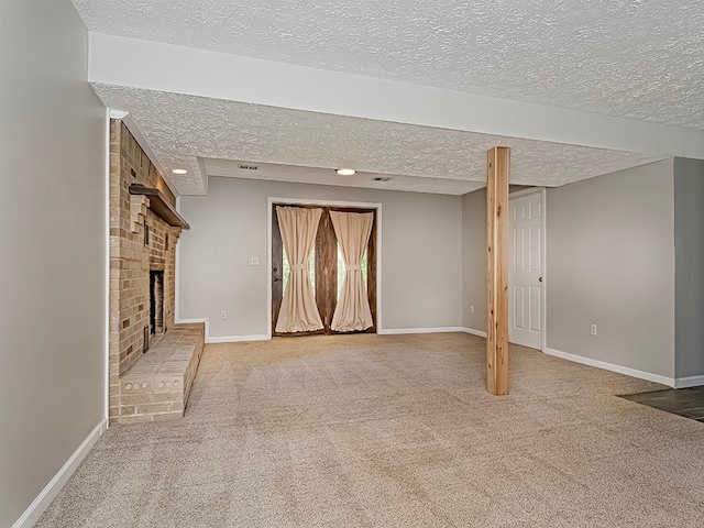 basement with a textured ceiling, a brick fireplace, and carpet floors