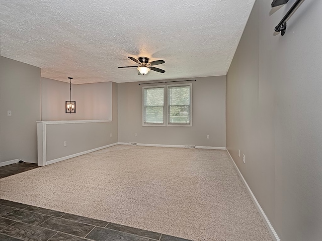 carpeted spare room featuring ceiling fan with notable chandelier and a textured ceiling