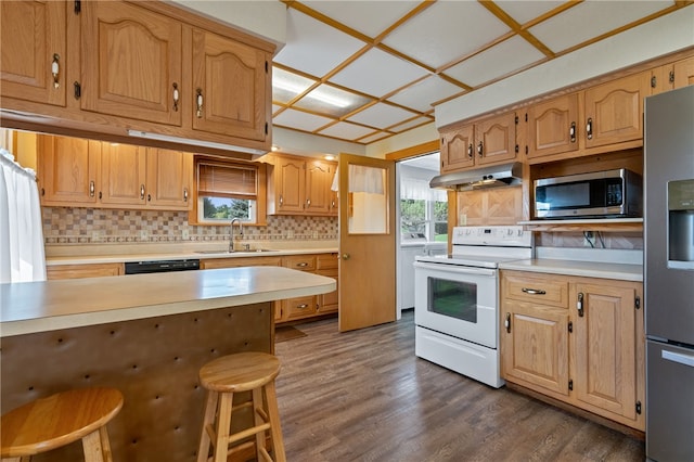 kitchen with stainless steel appliances, sink, a kitchen bar, dark hardwood / wood-style floors, and decorative backsplash