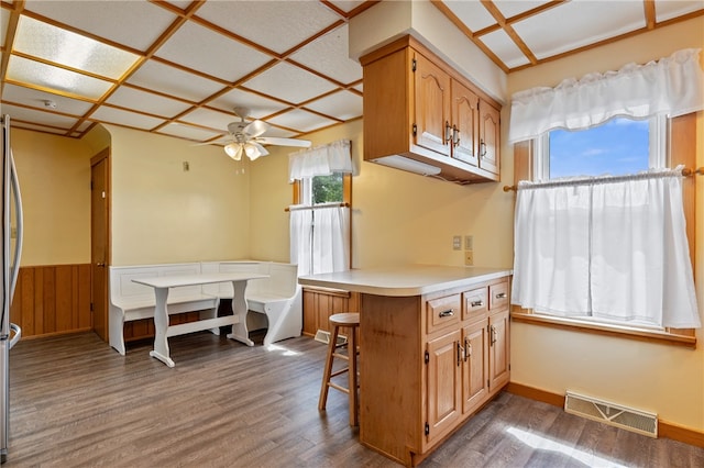 kitchen featuring dark wood-type flooring, ceiling fan, kitchen peninsula, and a breakfast bar