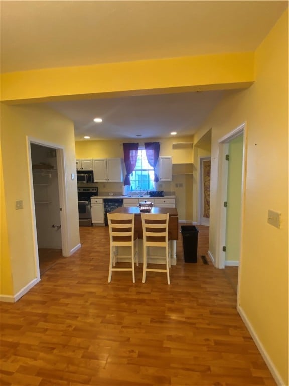 kitchen with white cabinets, appliances with stainless steel finishes, sink, and light hardwood / wood-style flooring