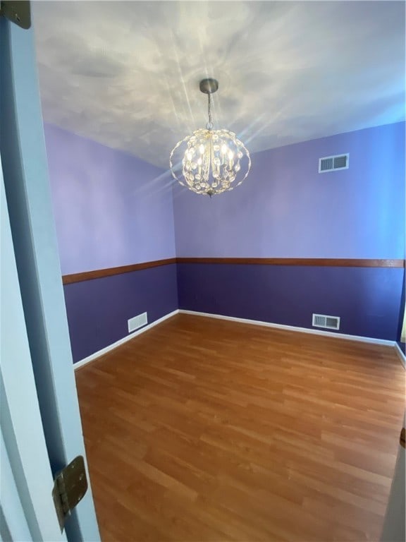 empty room featuring hardwood / wood-style flooring and a chandelier