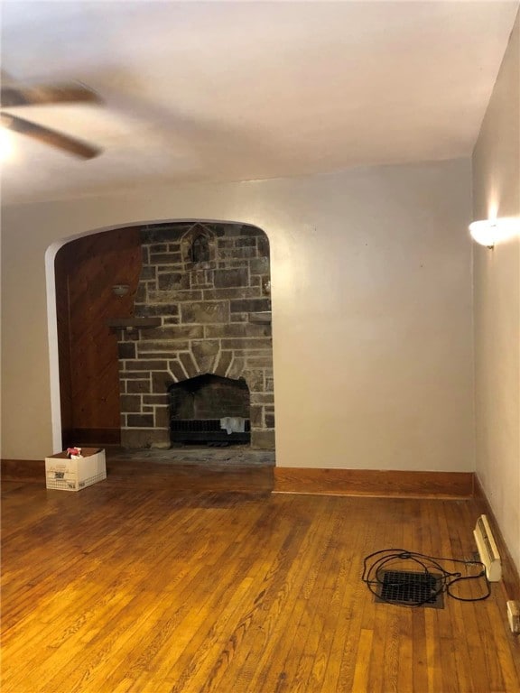 unfurnished living room with ceiling fan, hardwood / wood-style floors, and a fireplace