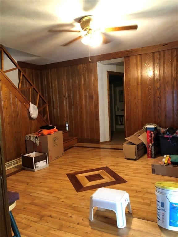 interior space with hardwood / wood-style floors, ceiling fan, and wooden walls