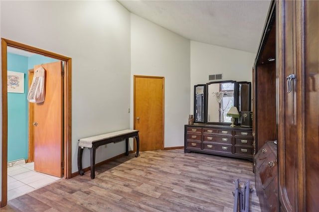 bedroom with light wood-type flooring and high vaulted ceiling