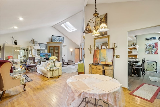 dining area featuring light hardwood / wood-style flooring, high vaulted ceiling, and a skylight