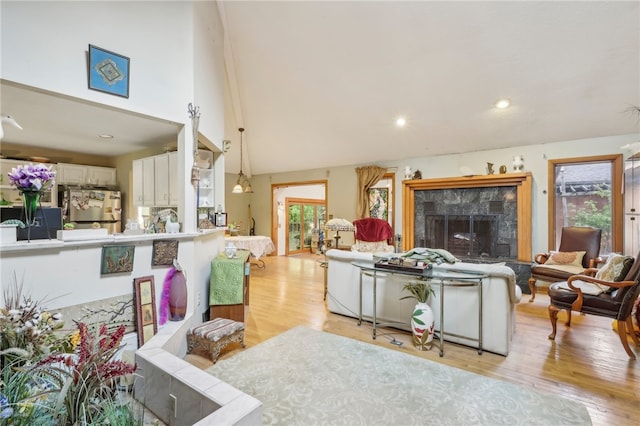 living room featuring vaulted ceiling, a premium fireplace, and light hardwood / wood-style flooring