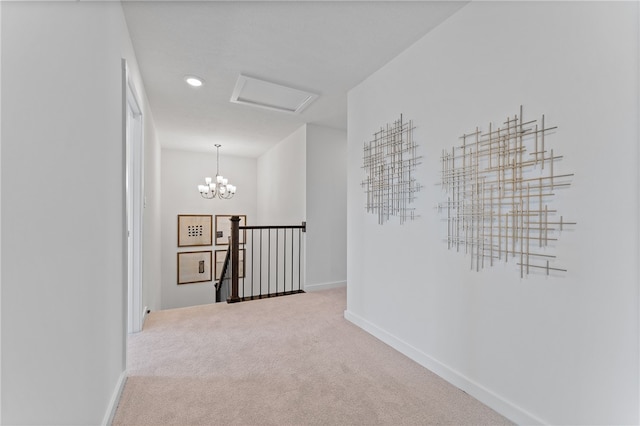 hall with an inviting chandelier and carpet floors