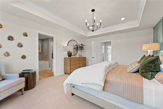 bedroom featuring light colored carpet, a raised ceiling, a chandelier, and ensuite bath