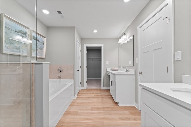 bathroom featuring hardwood / wood-style flooring, shower with separate bathtub, and vanity