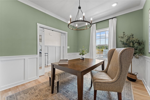 dining room with ornamental molding, a notable chandelier, and light hardwood / wood-style floors